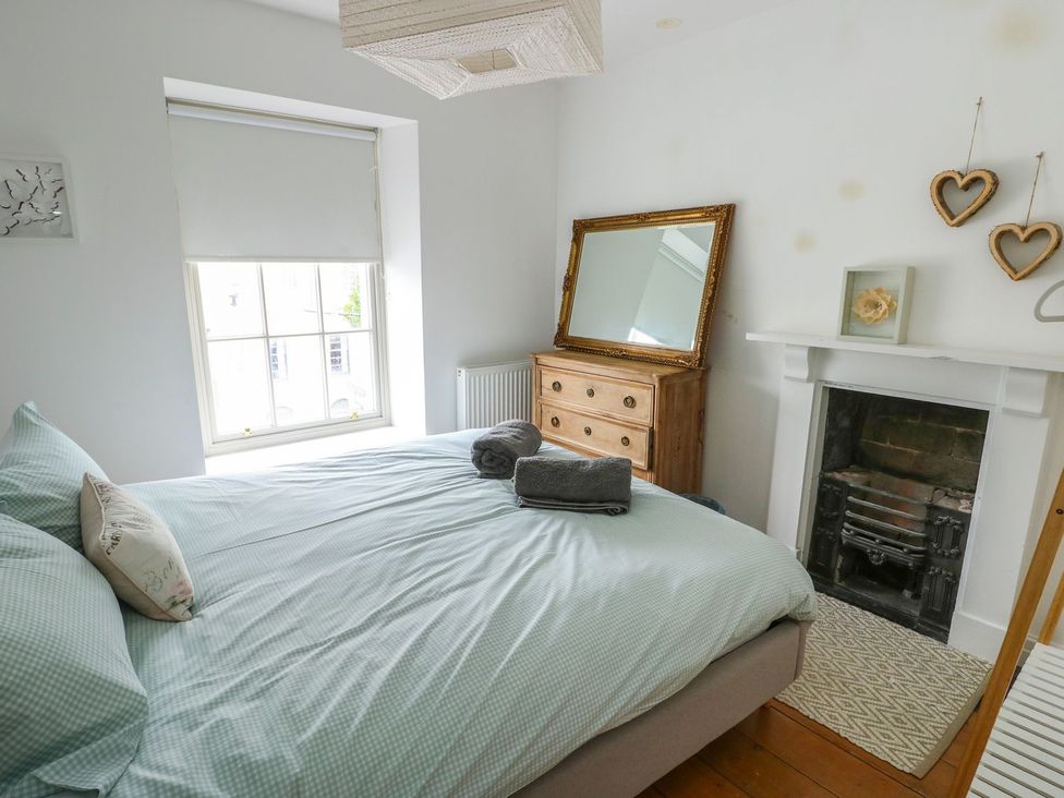 A bedroom with a bed and dresser at Tri Raglan Mawr in Beaumaris