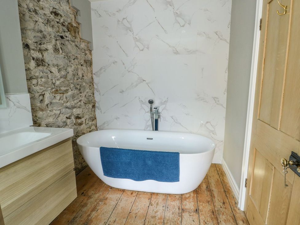 A bathroom with a bathtub and washbasin at Tri Raglan Mawr Beaumaris