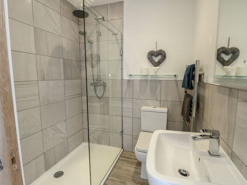 A bathroom with a shower, toilet, and sink at Tri Raglan Mawr in Beaumaris