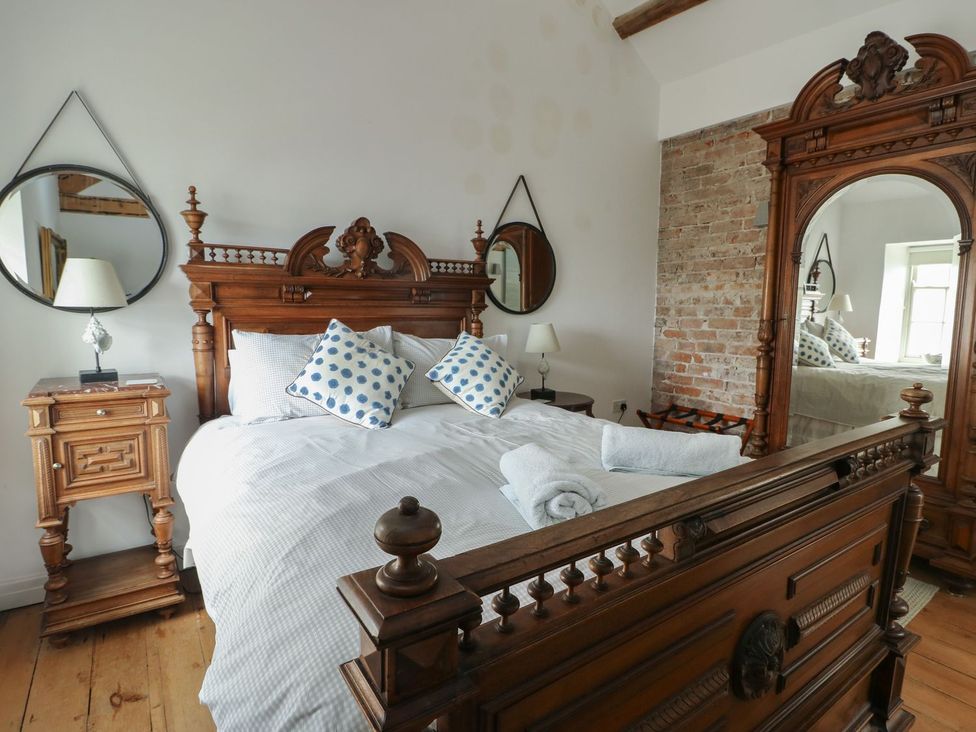 A bedroom with a bed and nightstand at Tri Raglan Mawr Beaumaris