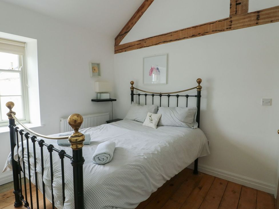 A bedroom with a bed and bedside lamp at Tri Raglan Mawr in Beaumaris