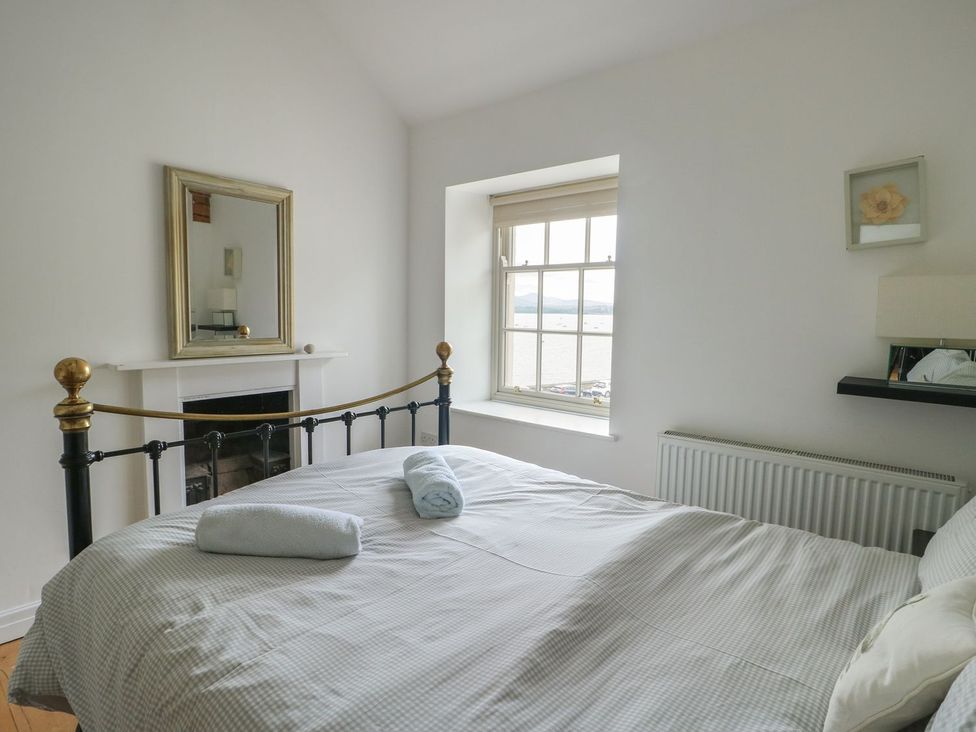 A bedroom with a bed and window at Tri Raglan Mawr in Beaumaris