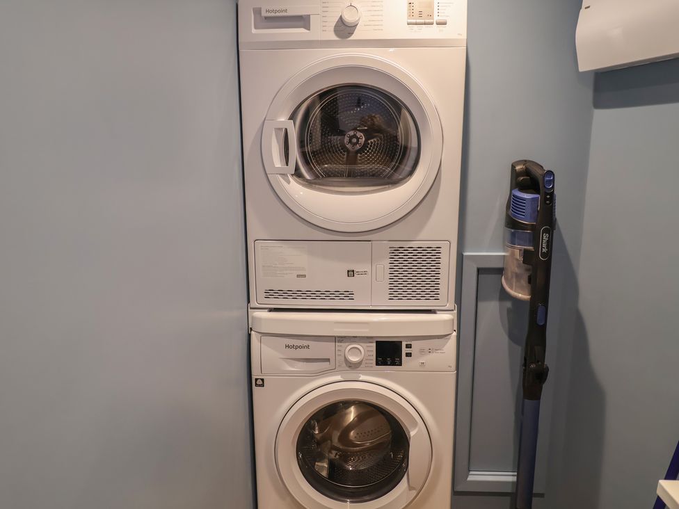 A washer and dryer stacked with a vacuum cleaner at Unit 2 in Ipswich