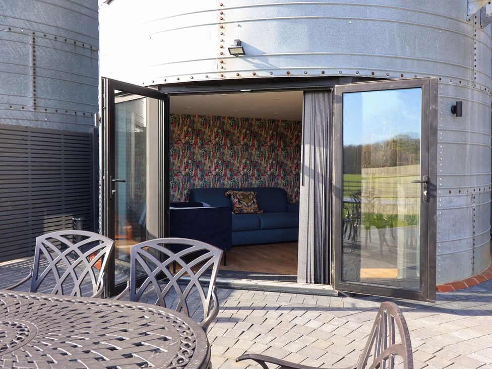 A patio with a table and chairs leading to a living area at The Barley Silo in Ipswich