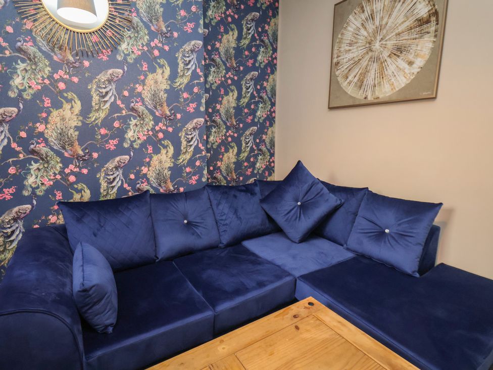 A living room with a blue sofa and wall decor at Apartment 2, Blackburn Heights in Bridlington