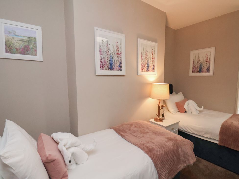 A bedroom with two beds and artwork on the wall at Apartment 2, Blackburn Heights in Bridlington