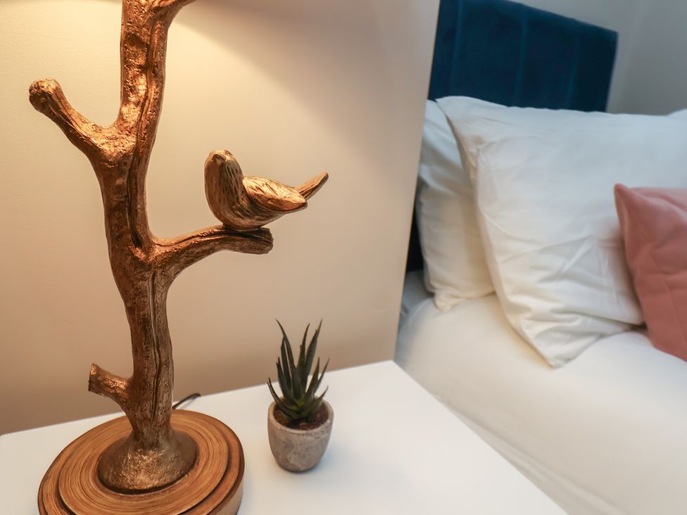 A bedside table with a lamp and a plant in Apartment 2, Blackburn Heights Bridlington