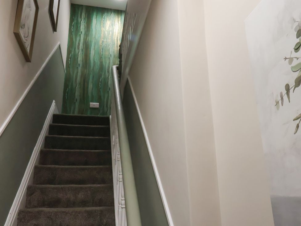 A staircase with green wall and framed pictures at Apartment 2, Blackburn Heights in Bridlington