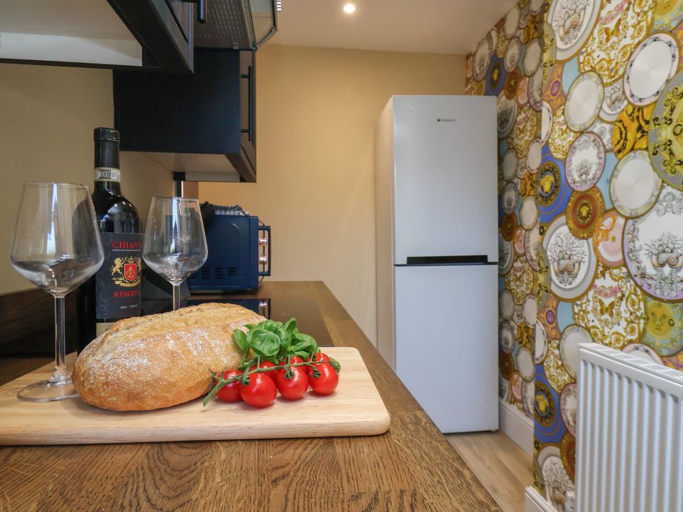 A kitchen with a bottle of wine and bread on a counter at Apartment 2, Blackburn Heights in Bridlington