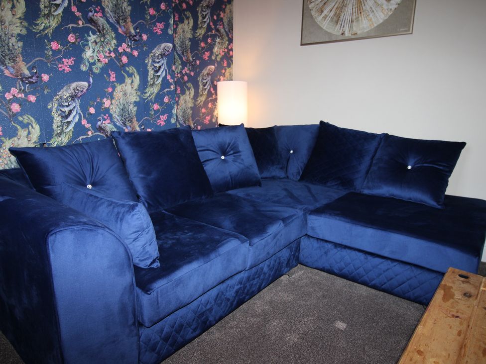 A living room with a blue sofa and a lamp at Blackburn Heights Apartment in Bridlington