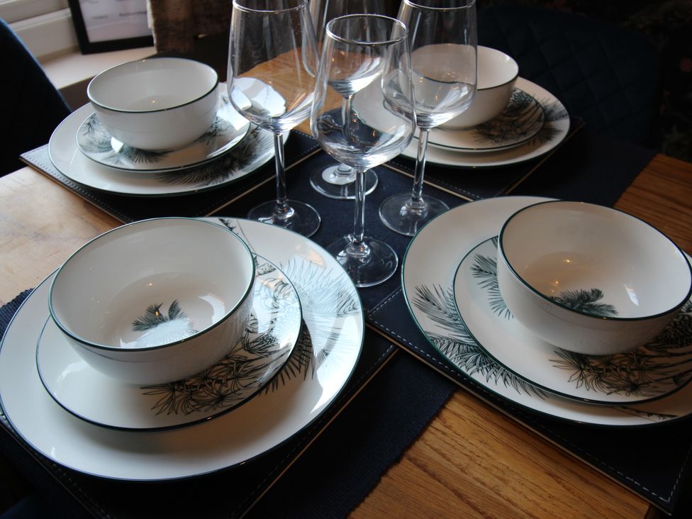A dining table set with plates, bowls, and glasses at Blackburn Heights Apartment in Bridlington