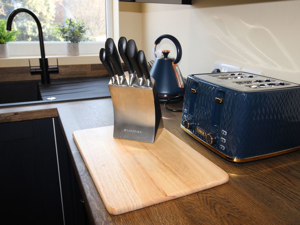 A kitchen with knife block, chopping board, toaster and kettle at Blackburn Heights Apartment in Bridlington