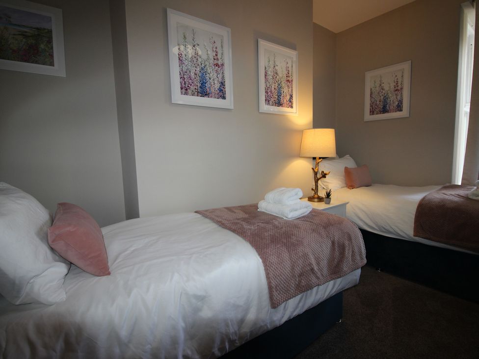 A bedroom with two beds and a lamp on a bedside table at Blackburn Heights Apartment Bridlington