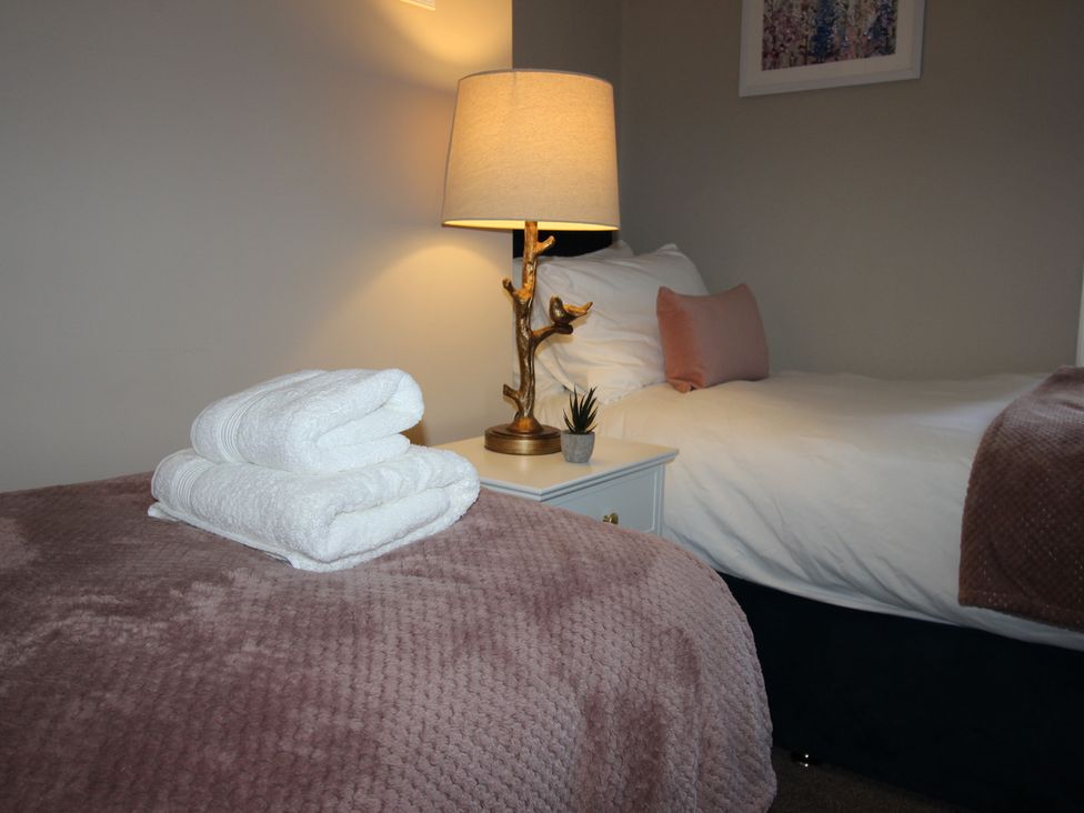 A bedroom with towels and a lamp at Blackburn Heights Apartment in Bridlington