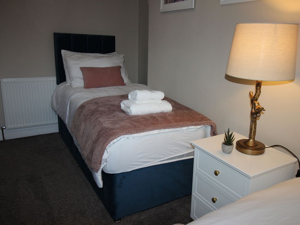 A single bed with towels and a lamp at Blackburn Heights Apartment in Bridlington