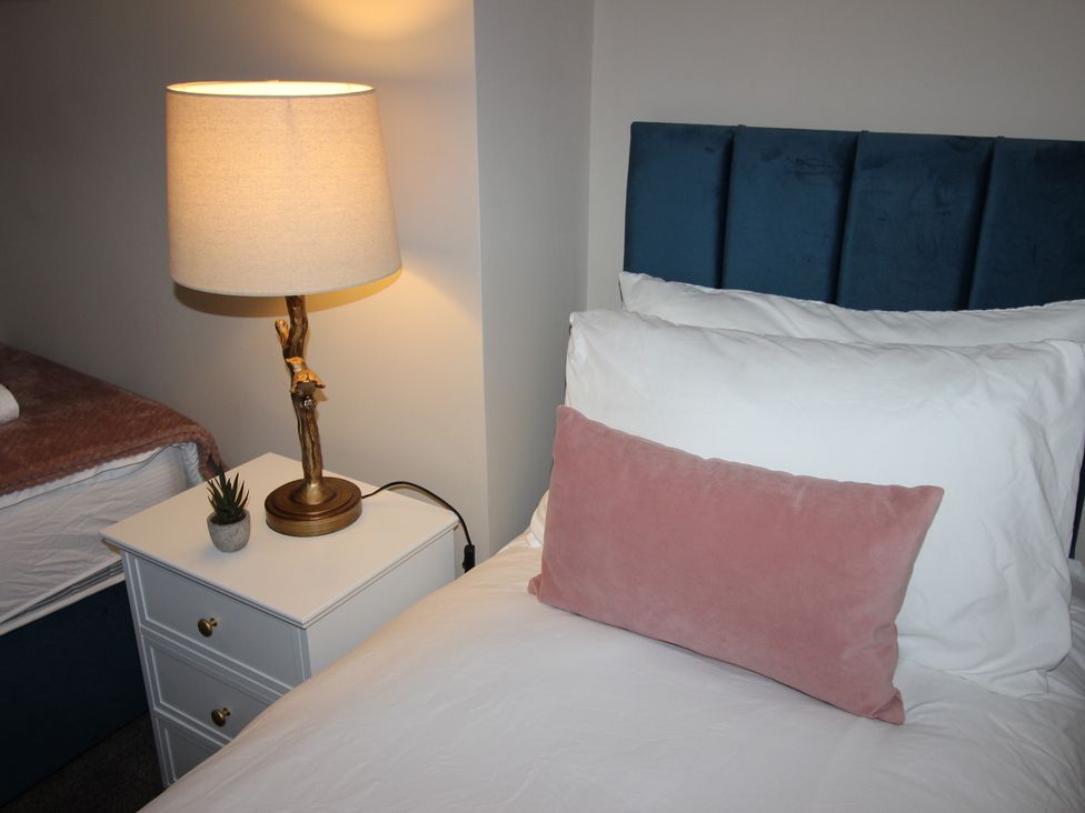 A bedroom with a bed, lamp, and nightstand at Blackburn Heights Apartment in Bridlington