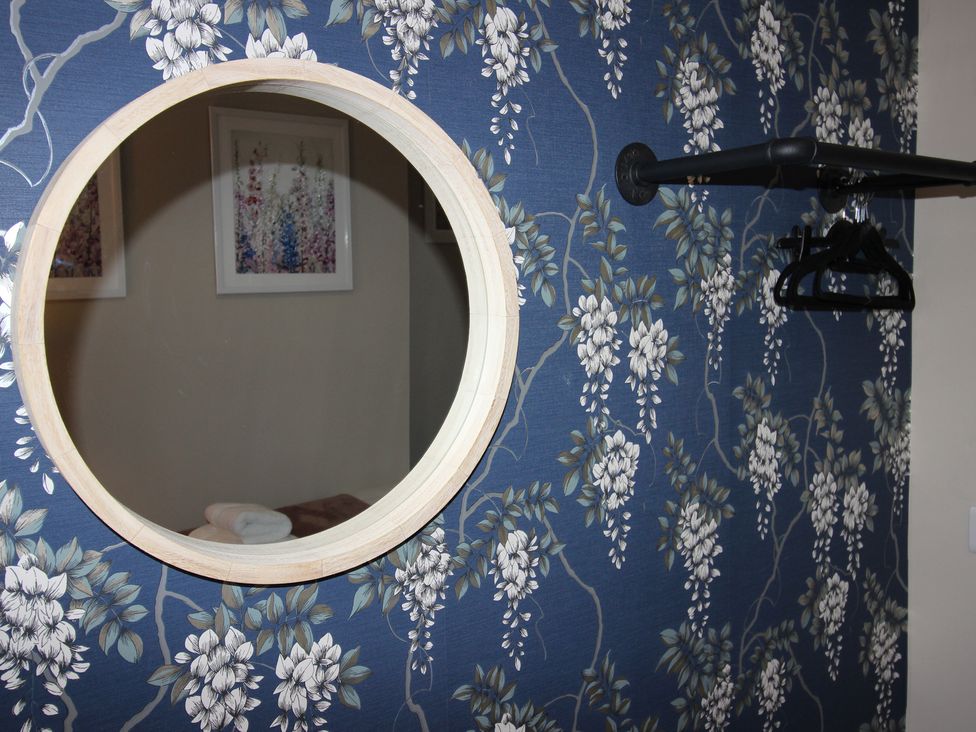 A mirror and clothes hanger on a floral wall at Blackburn Heights Apartment in Bridlington