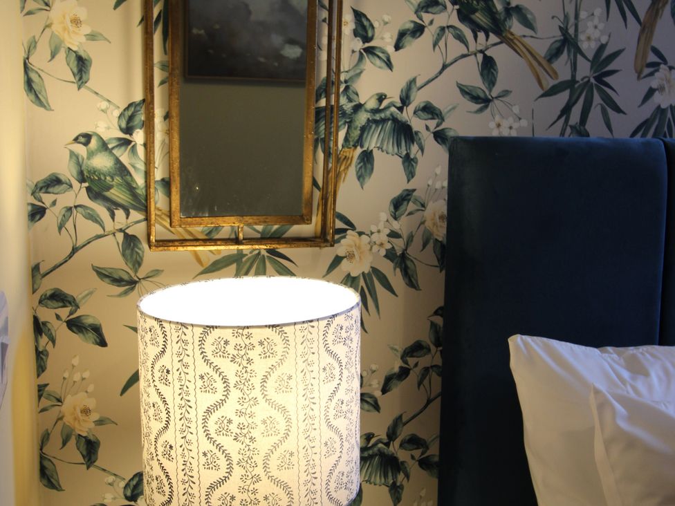 A bedroom with a lamp and mirror at Blackburn Heights Apartment in Bridlington