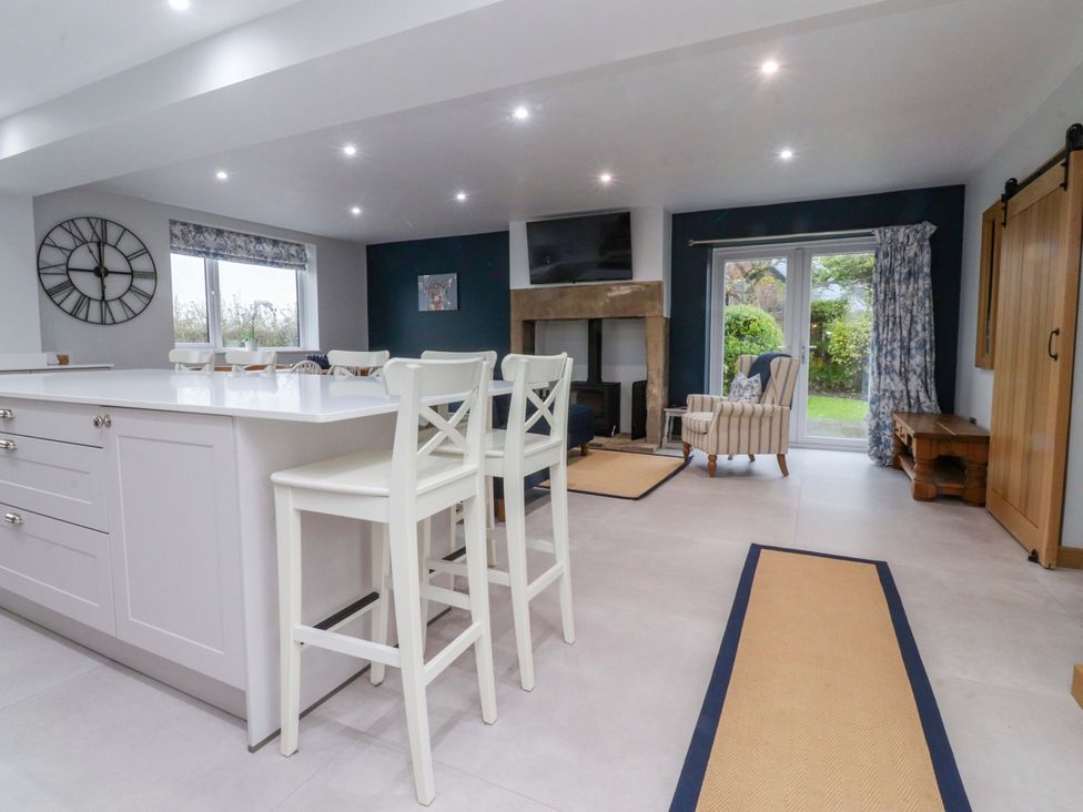 A kitchen with bar stools and a fireplace at Brook House in Broughton, Lancashire
