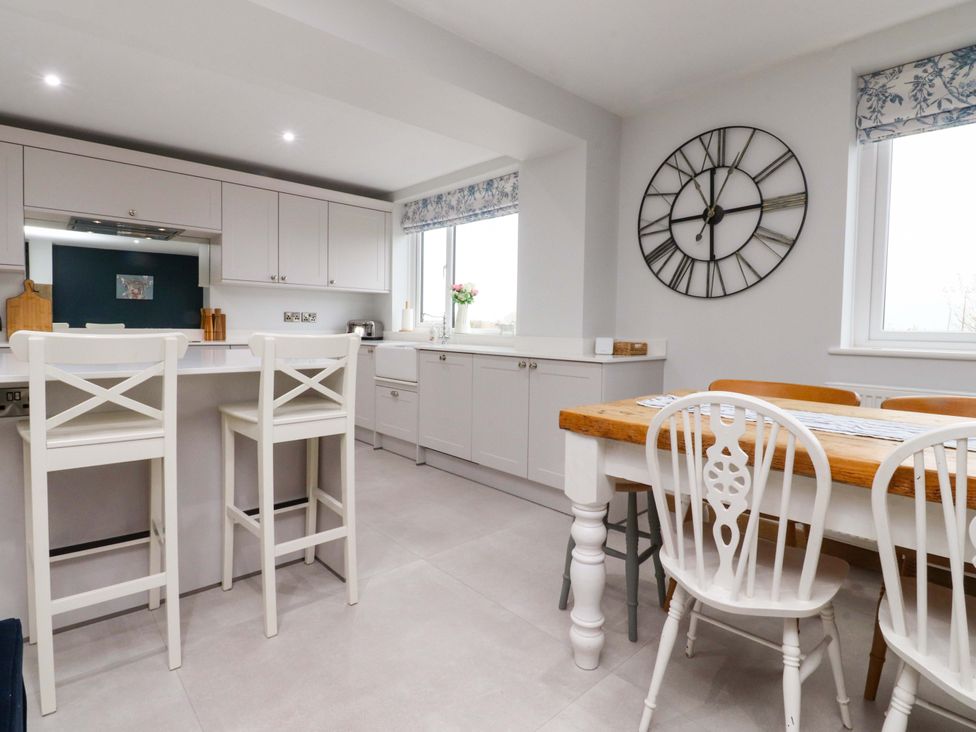 A kitchen with a dining area and bar stools at Brook House in Broughton, Lancashire