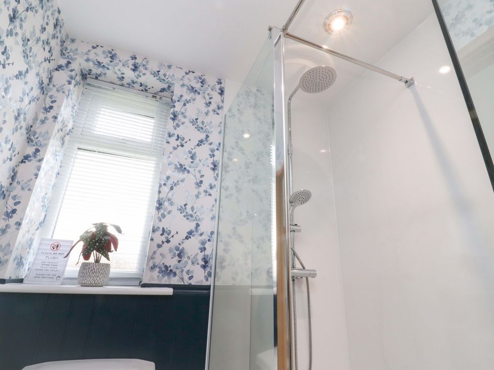A bathroom featuring a shower, toilet, and window at Brook House in Broughton, Lancashire