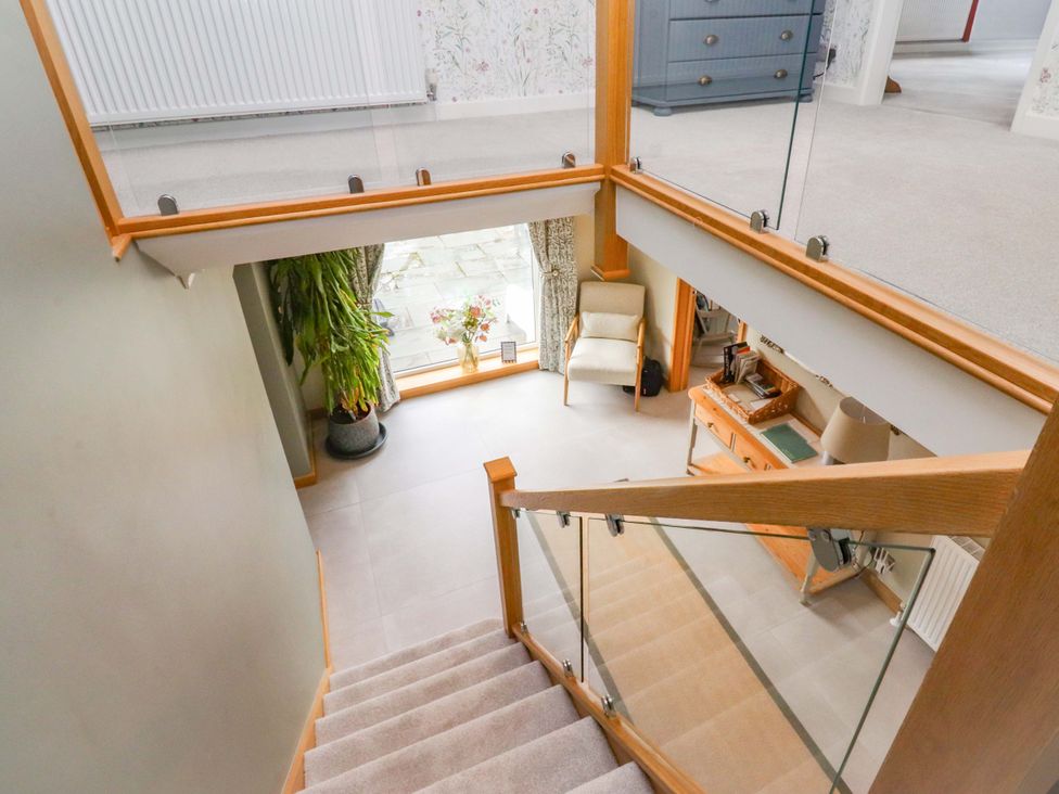 A staircase leading to a hallway with a plant and chair at Brook House in Broughton, Lancashire