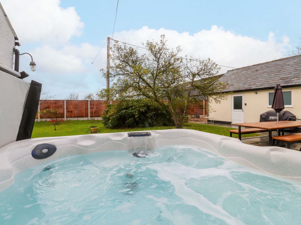 A hot tub with a table and umbrella in a garden at Brook House in Broughton, Lancashire