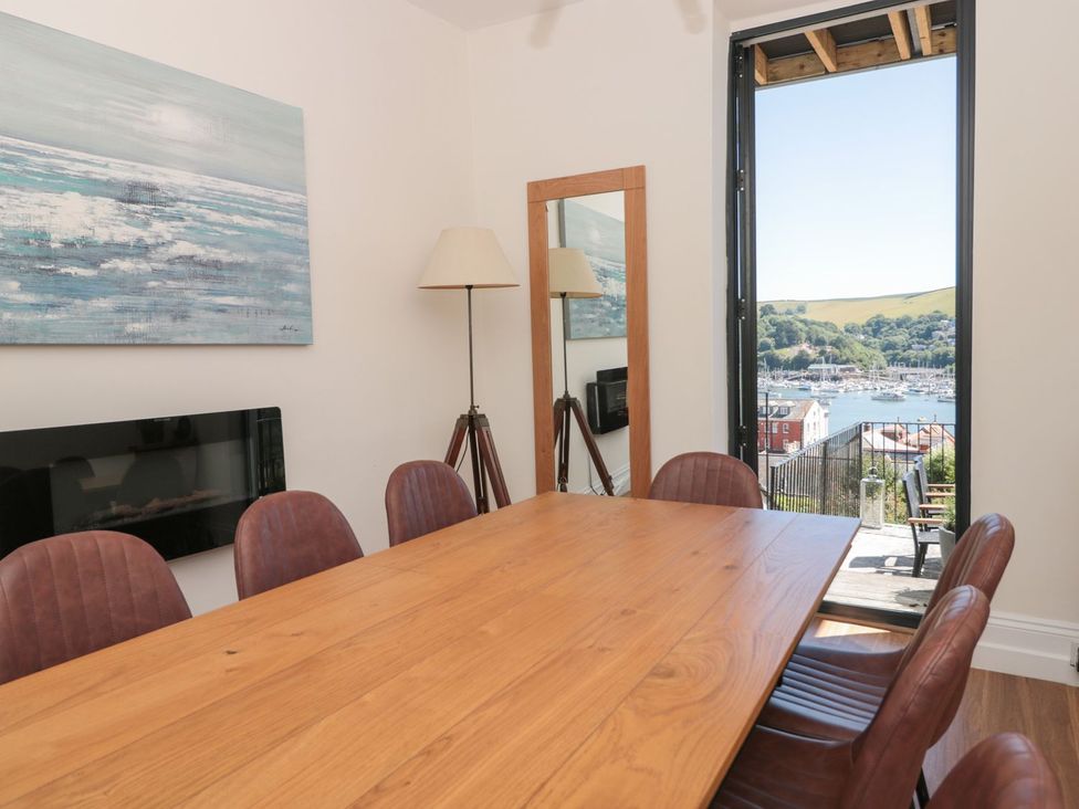 A dining room with a table and chairs overlooking a marina at Ty'r Ddraig Dartmouth
