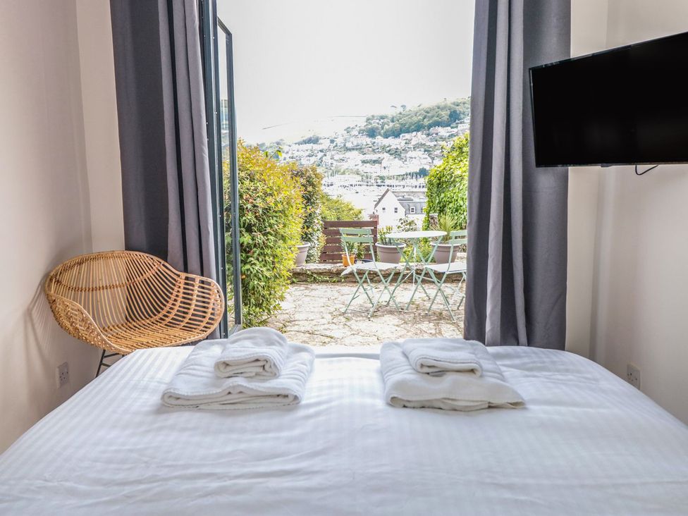 A bedroom with a bed and a view of the patio at Ty'r Ddraig in Dartmouth