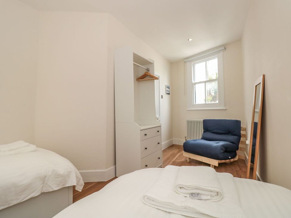 A bedroom with two beds and a wardrobe at Ty'r Ddraig Dartmouth