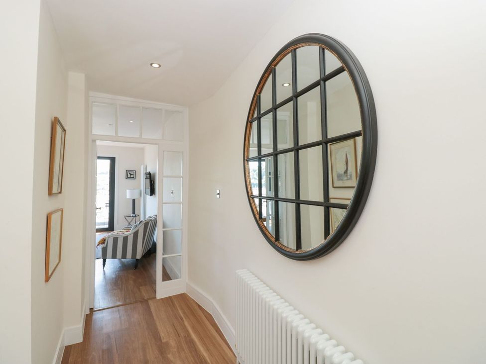 A hallway with a mirror and paintings on the wall at Ty'r Ddraig in Dartmouth