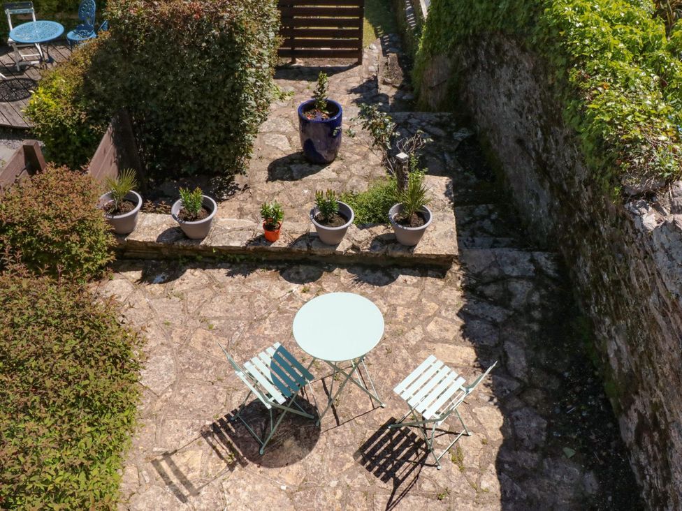 A garden with a stone patio and a round table at Ty'r Ddraig in Dartmouth