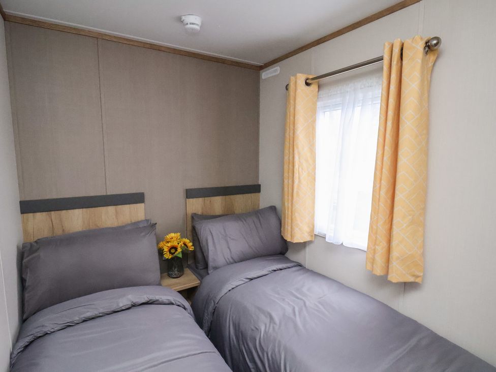 A bedroom with two beds and a vase of flowers at No. 7 Ivy in Scarborough