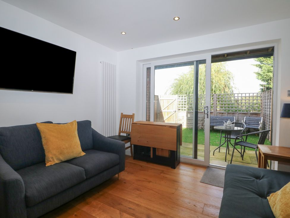 A living room with sofa and sliding doors leading to the garden at No 1 The Crickets in Bognor Regis