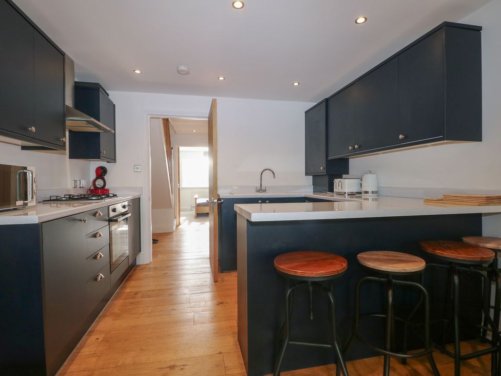 A kitchen with dark cabinets and a gas stove at No 1 The Crickets in Bognor Regis