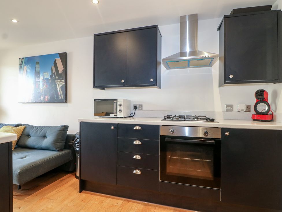 A kitchen with cabinets, oven, and a sofa at No 1 The Crickets Bognor Regis