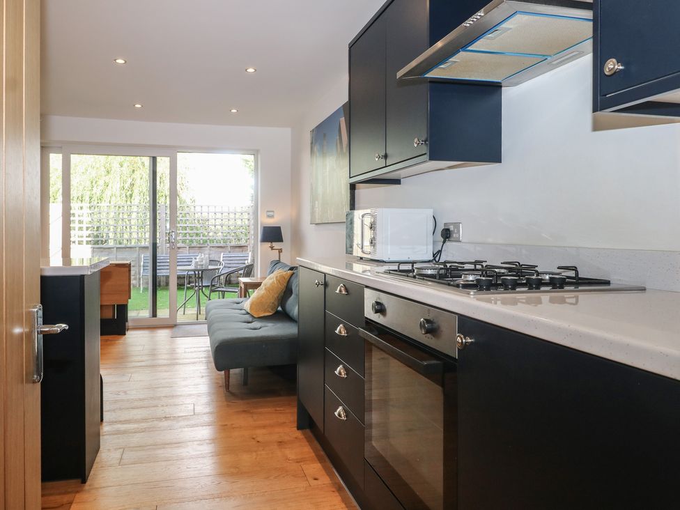 A kitchen with a stove, oven, microwave and sitting area at No 1 The Crickets Bognor Regis