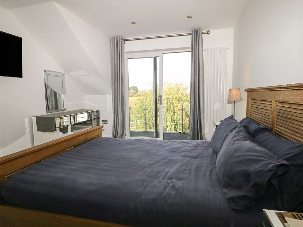 A bedroom with a bed and a door leading to a balcony at No 1 The Crickets in Bognor Regis