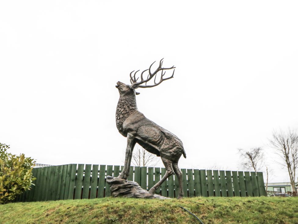 A deer statue next to a green fence at Plot 42 in Carlisle
