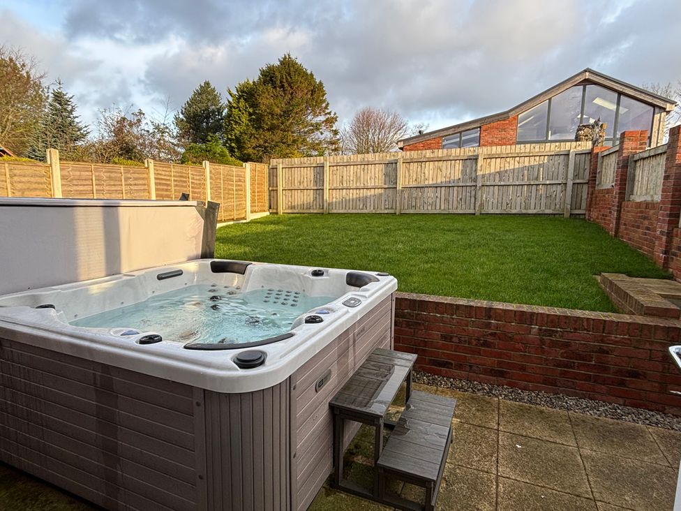 A garden with a hot tub and grass area at The Nest in Buckton near Bridlington