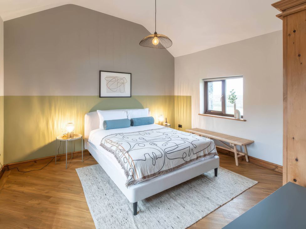 A bedroom with a bed, nightstand, and window at Black Bird Cottage in Llangaffo
