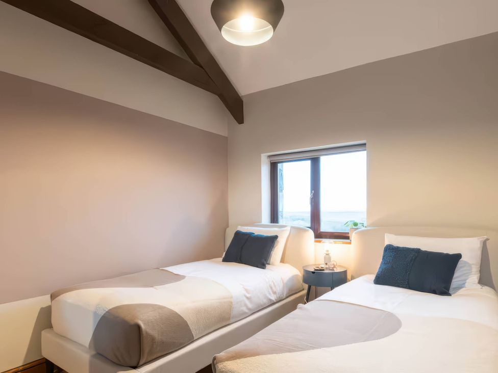 A bedroom with two beds and a window at Black Bird Cottage Llangaffo