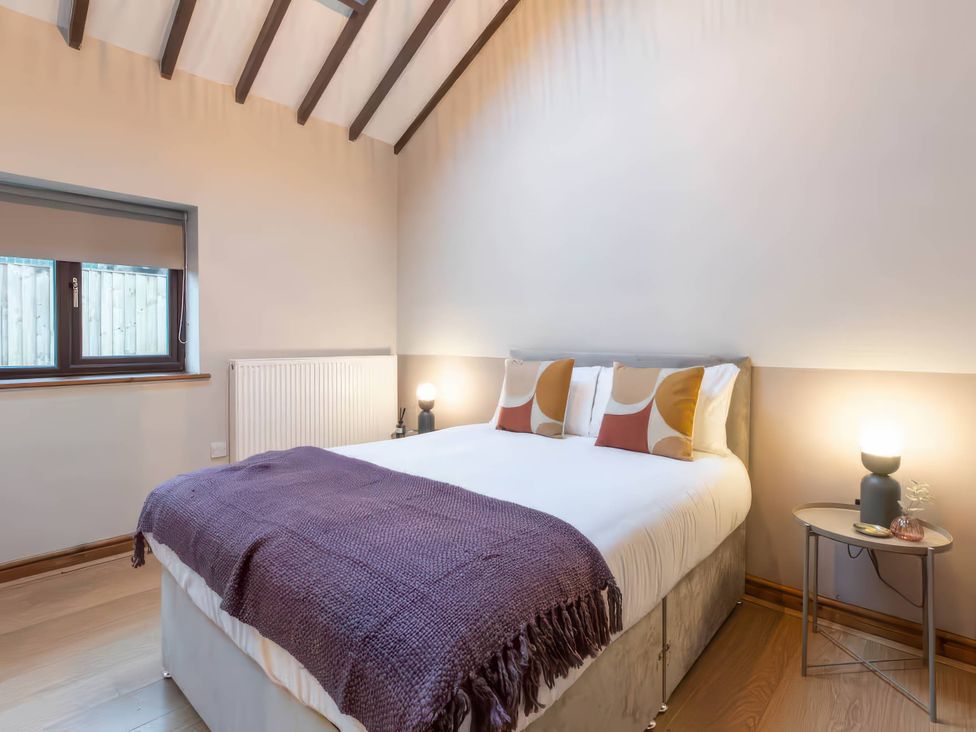A bedroom with a bed and window at Black Bird Cottage in Llangaffo