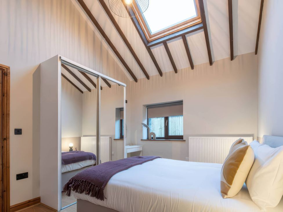 A bedroom with a bed and wardrobe at Black Bird Cottage in Llangaffo