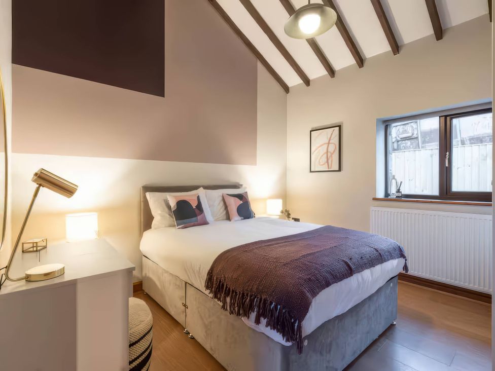 A bedroom with a bed and lamp at Black Bird Cottage in Llangaffo
