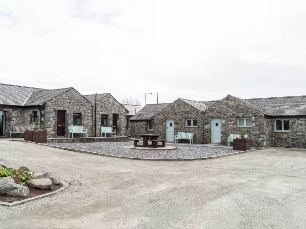 An outdoor area with stone cottages and benches at Black Bird Cottage Llangaffo