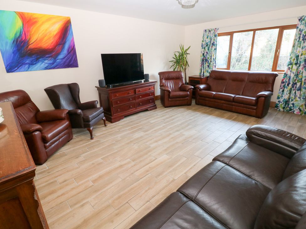 A living room with leather sofas and a television at Ty-Gan Dderwen in Llanelli