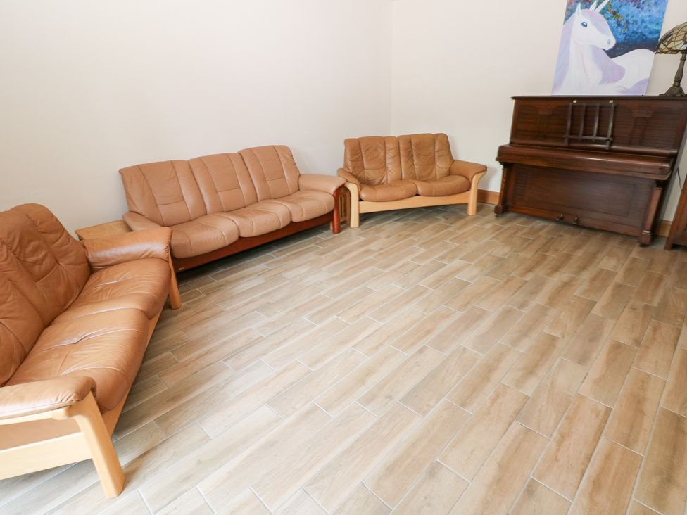 A living room with sofas and a piano at Ty-Gan Dderwen in Llanelli