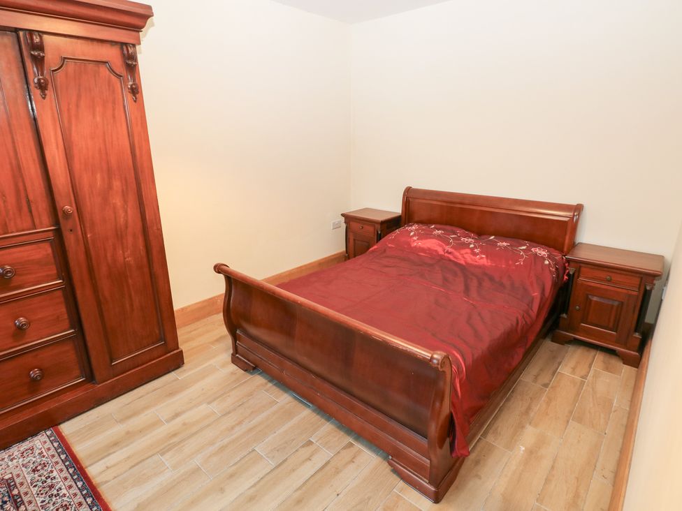 A bedroom with a bed and wardrobe at Ty-Gan Dderwen in Llanelli