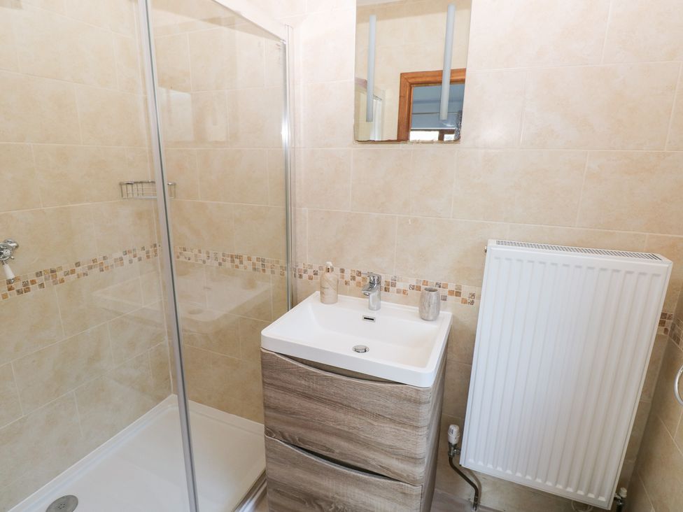 A bathroom with a shower, sink, and radiator at Ty-Gan Dderwen in Llanelli
